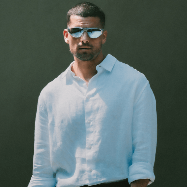 Man wearing a white shirt and sunglasses against a dark background