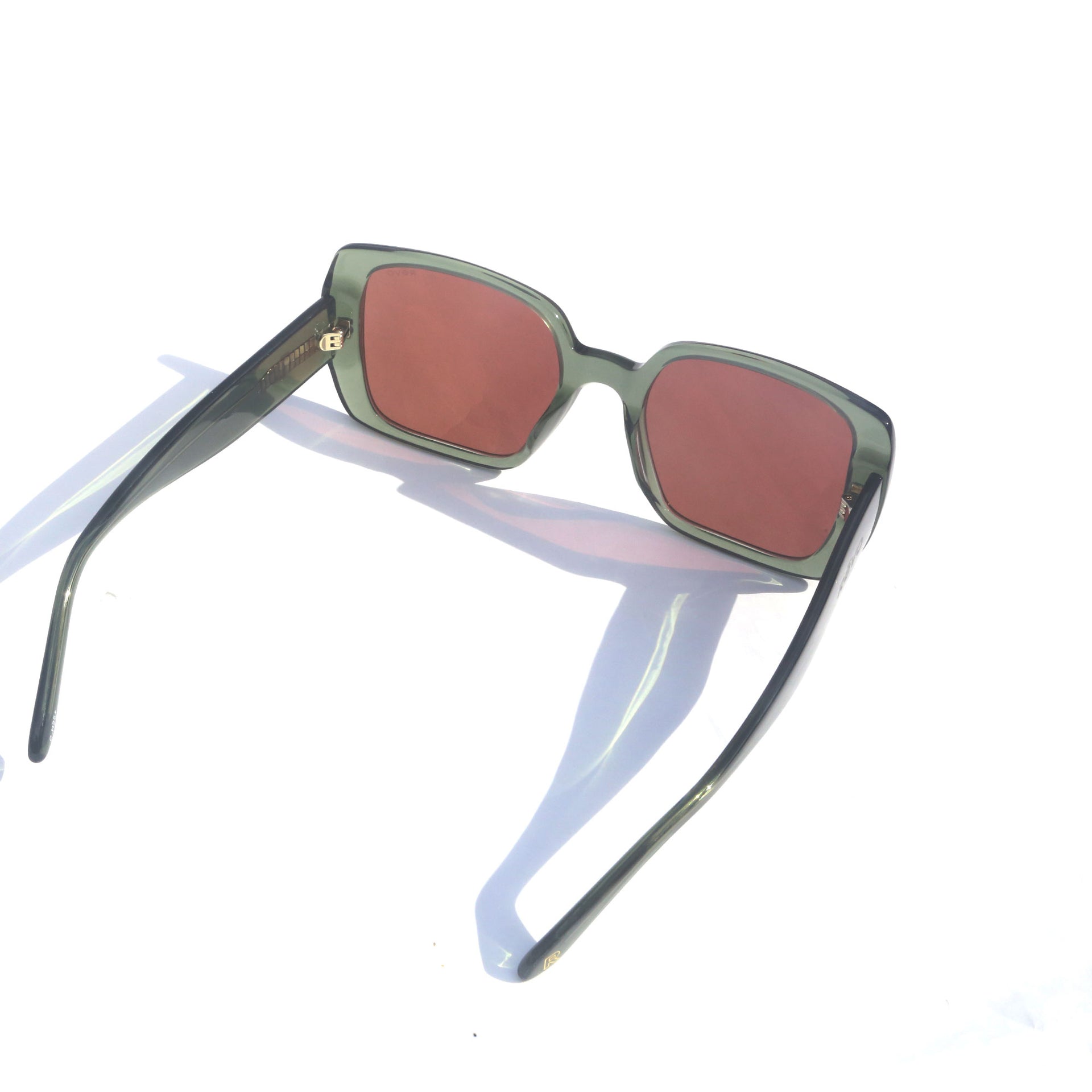 Sunglasses with red lenses and green frames on a white background
