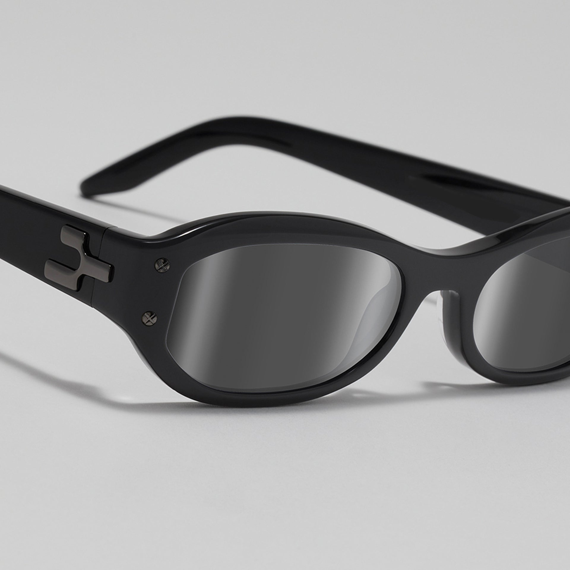 Black sunglasses with reflective lenses on a light gray background