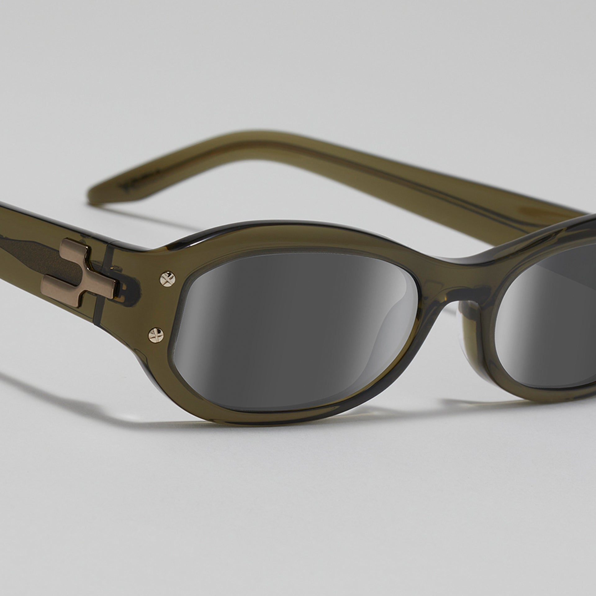 Sunglasses with green frame and dark lenses on a light gray background