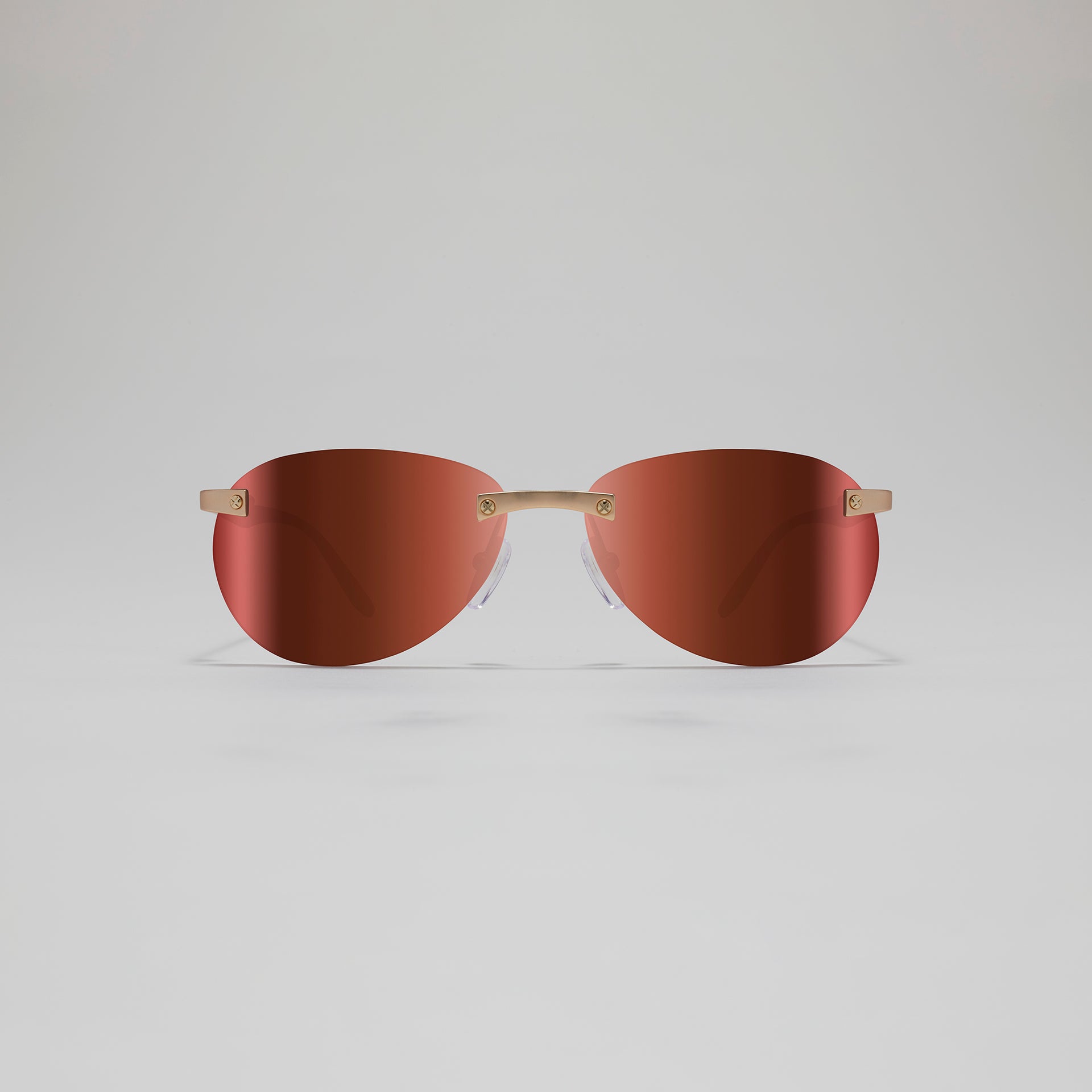 Sunglasses with brown lenses and gold frames on a light gray background