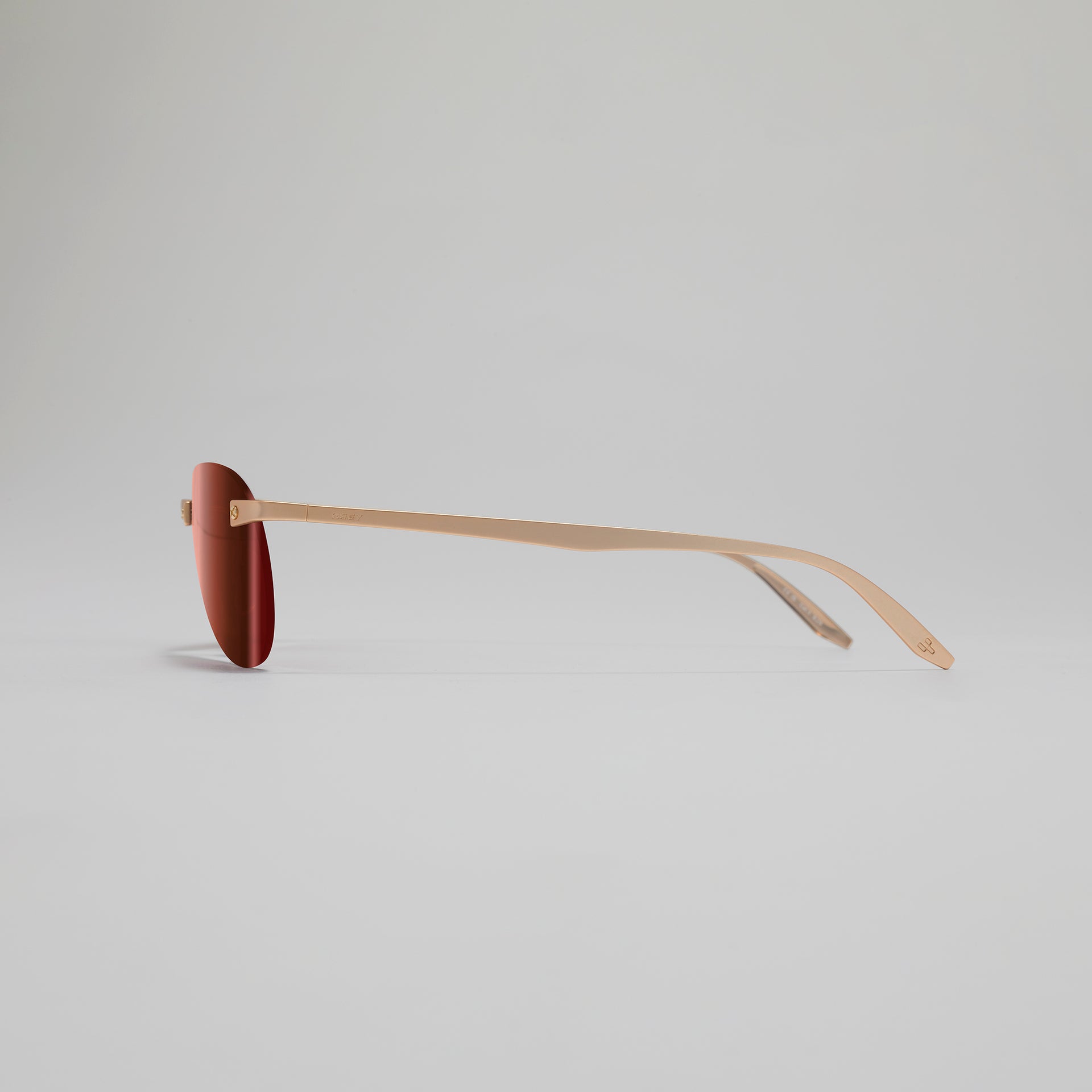 Sunglasses with a brown frame and red lens on a light gray background