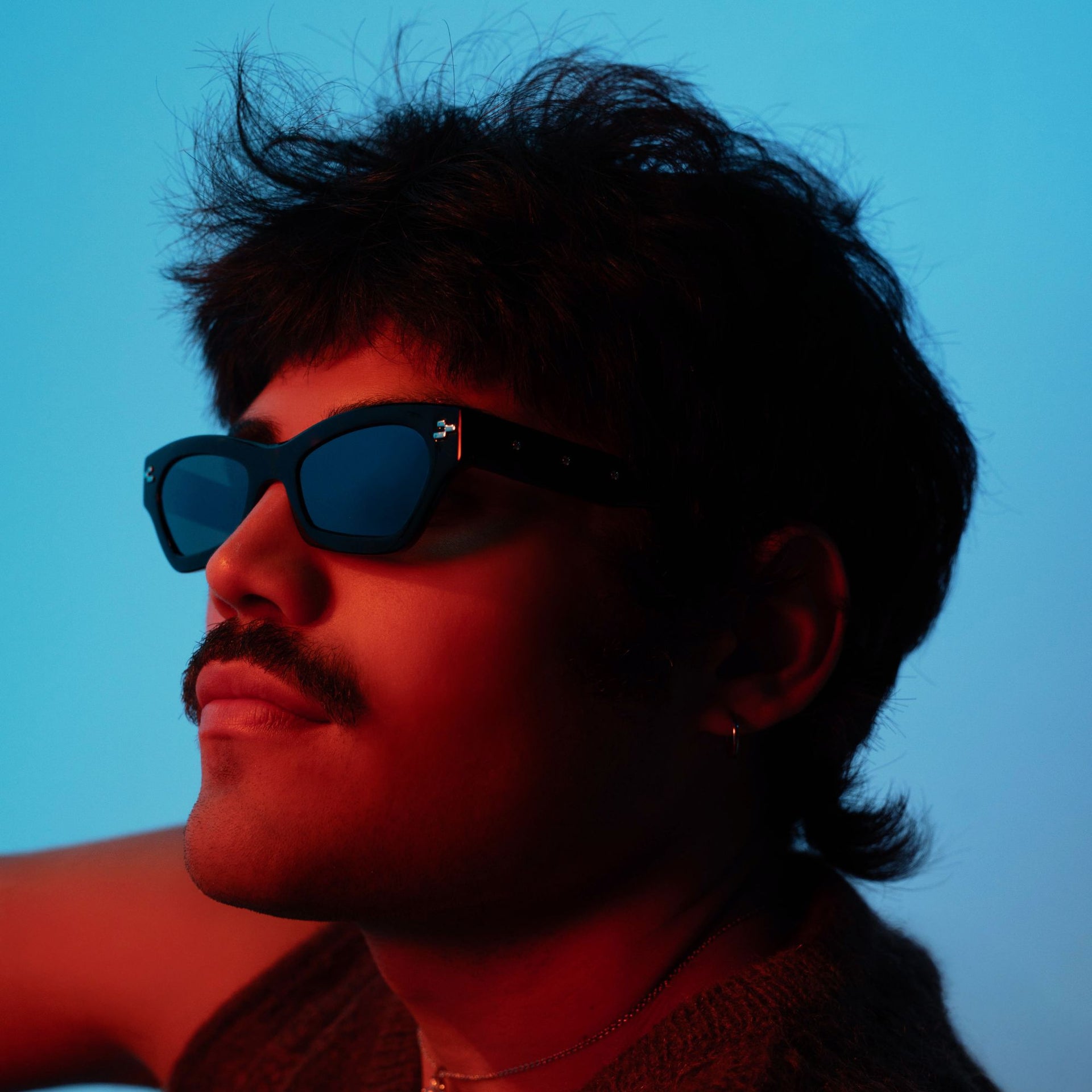Person wearing sunglasses with a blue background