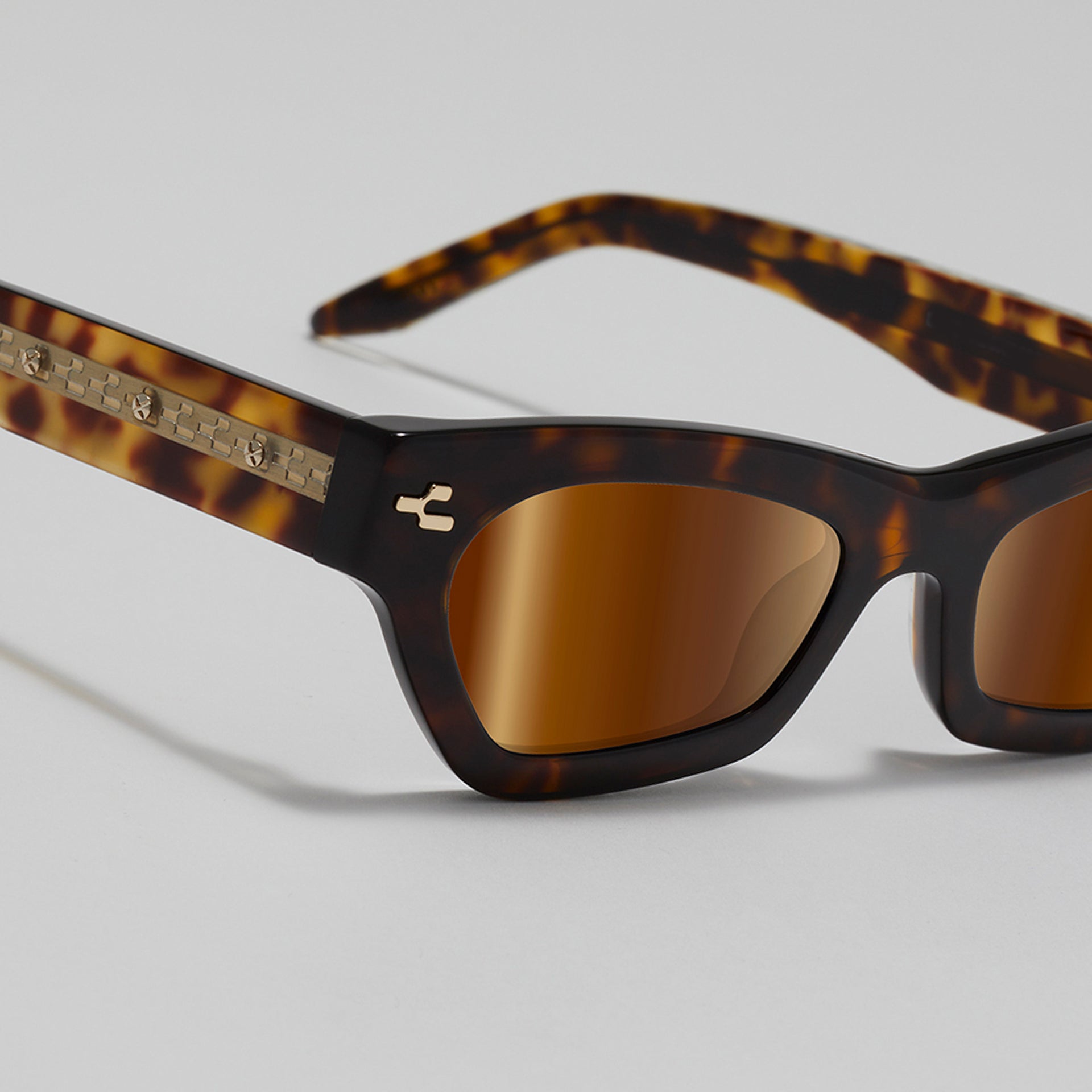 Sunglasses with tortoiseshell frame and brown lenses on a light gray background