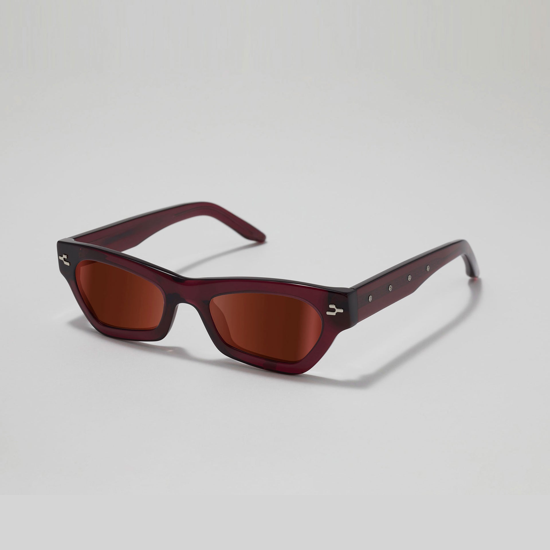 Sunglasses with a maroon frame and brown lenses on a light gray background