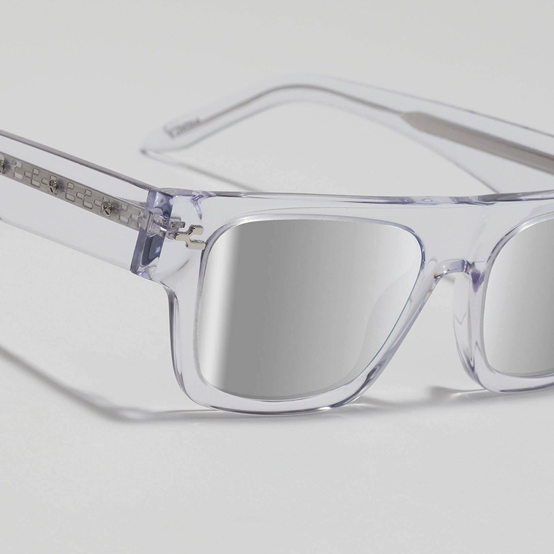 Clear sunglasses with reflective lenses on a light gray background