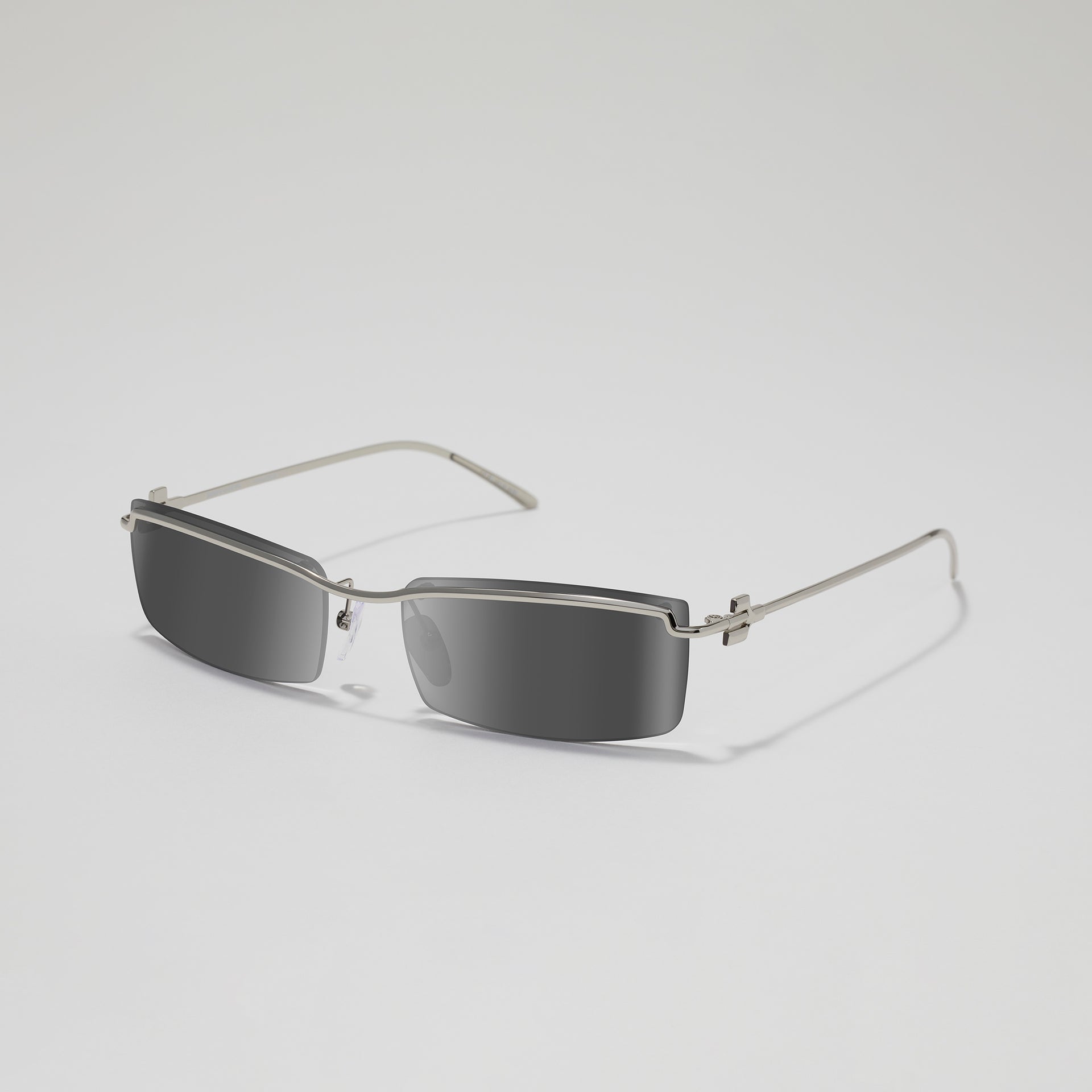 Sunglasses with thin metal frame and dark lenses on a light gray background