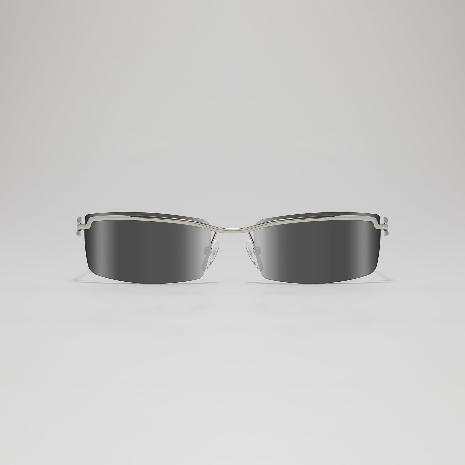 Sunglasses with a silver frame and dark lenses on a light gray background