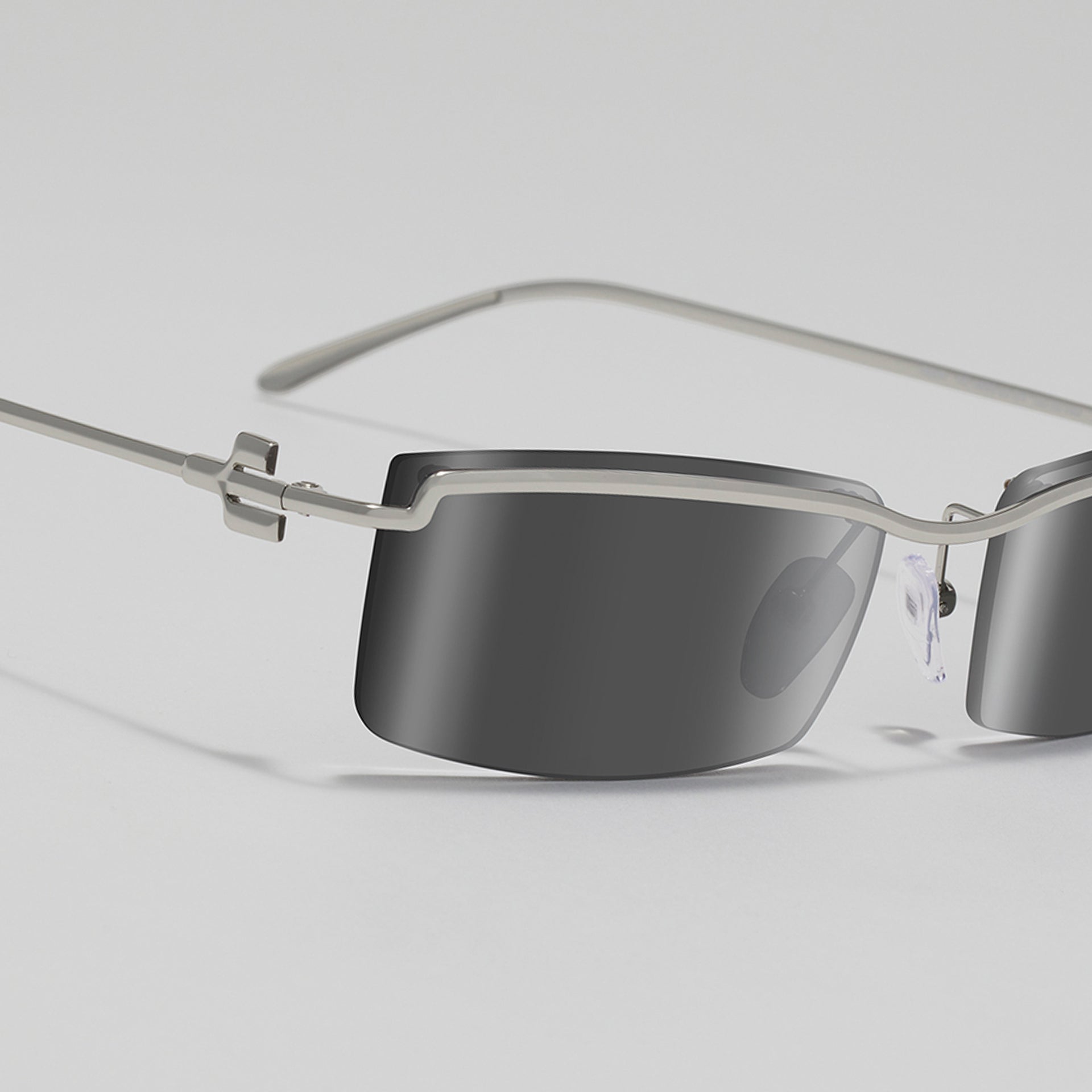 Sleek sunglasses with metallic frame and dark lenses on a light gray background