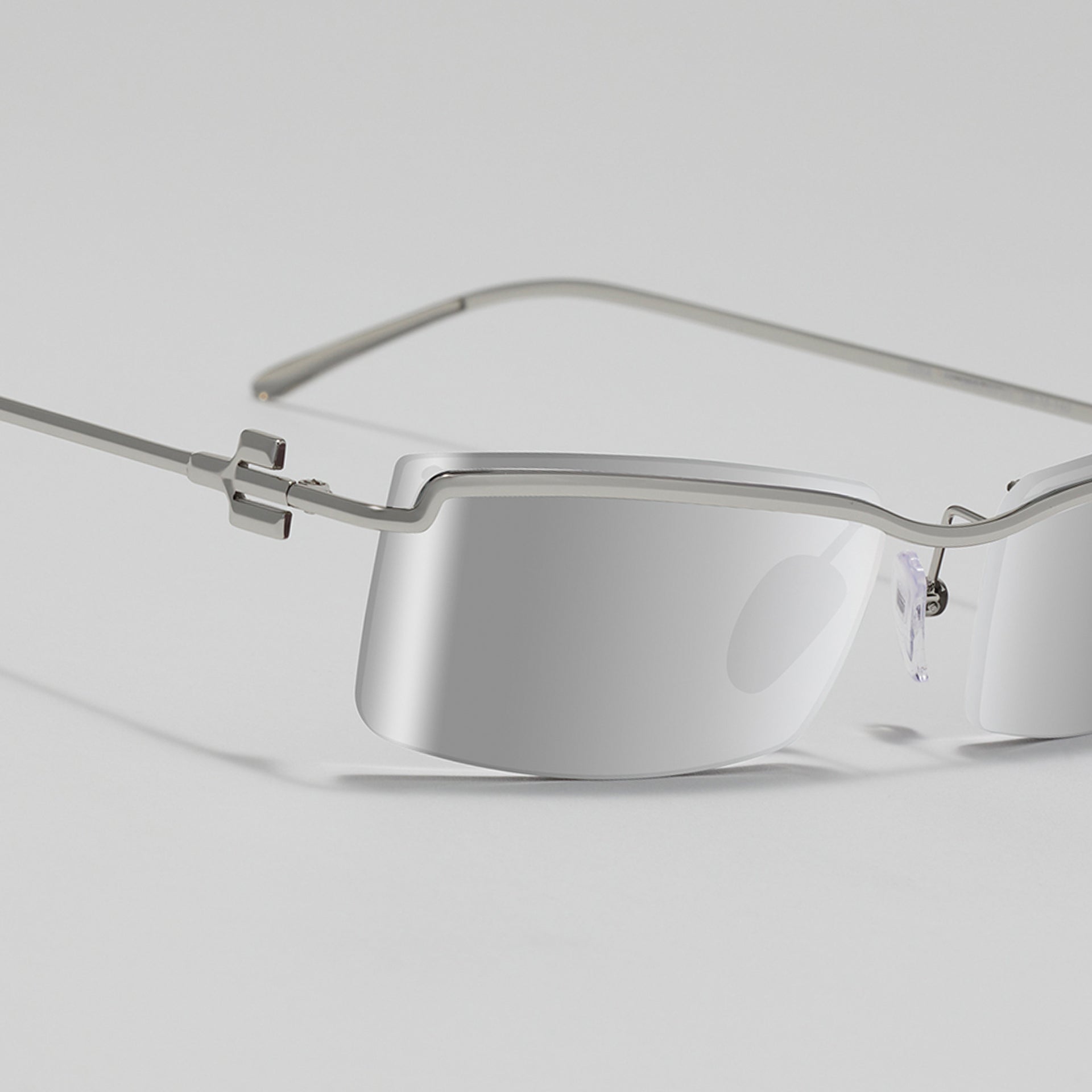 Silver rimless eyeglasses on a light gray background