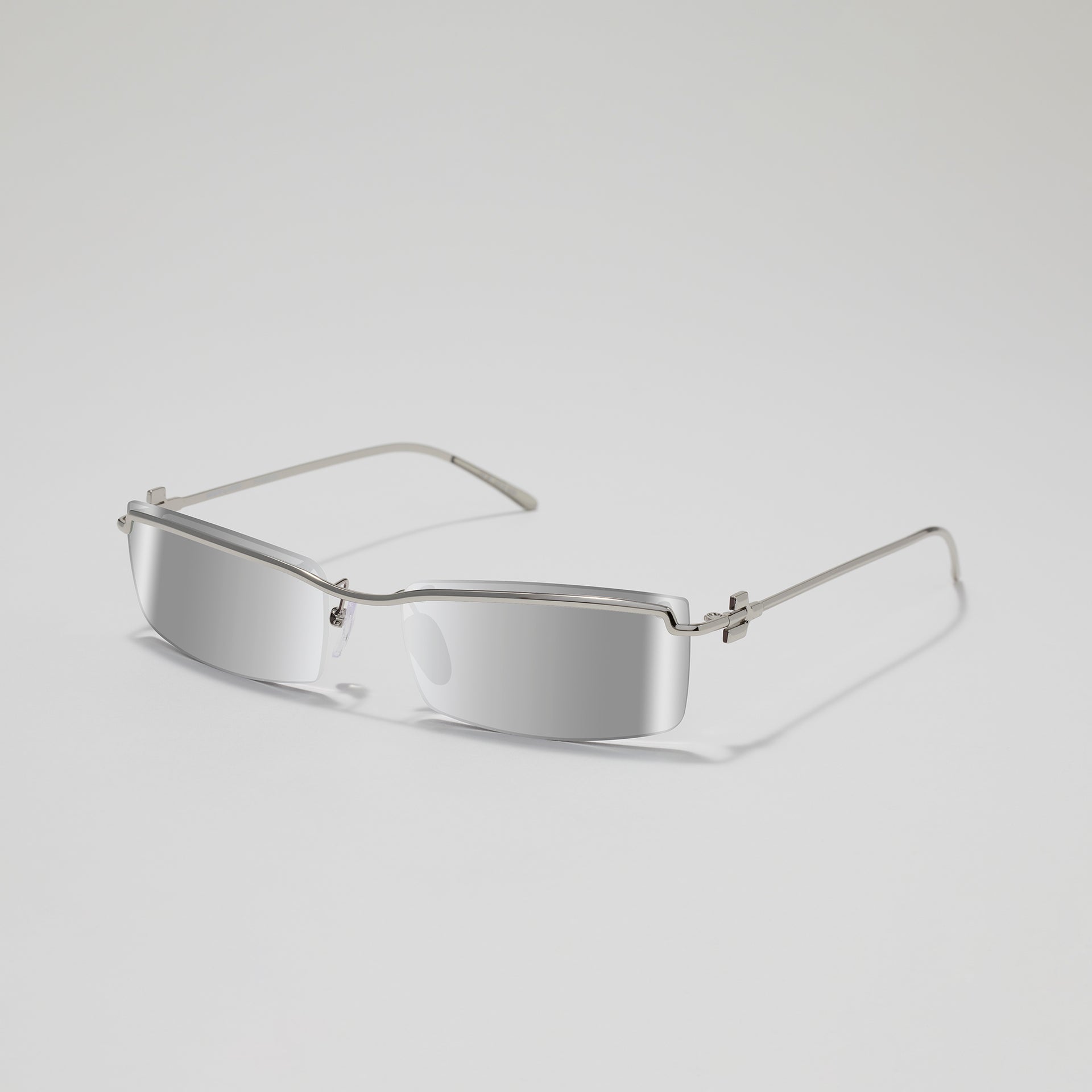Silver sunglasses with a minimalist design on a light gray background