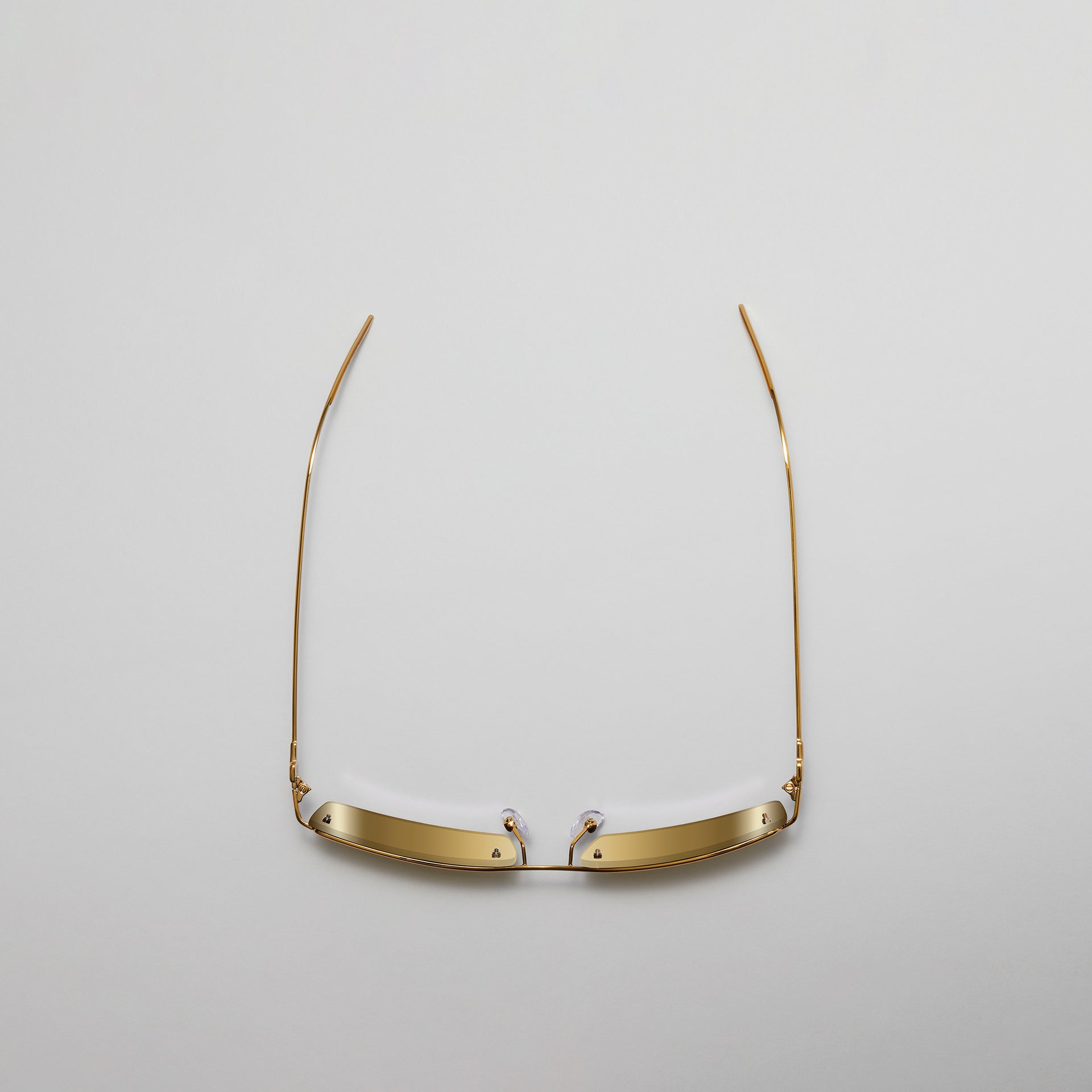 Gold eyeglass frame on a light gray background