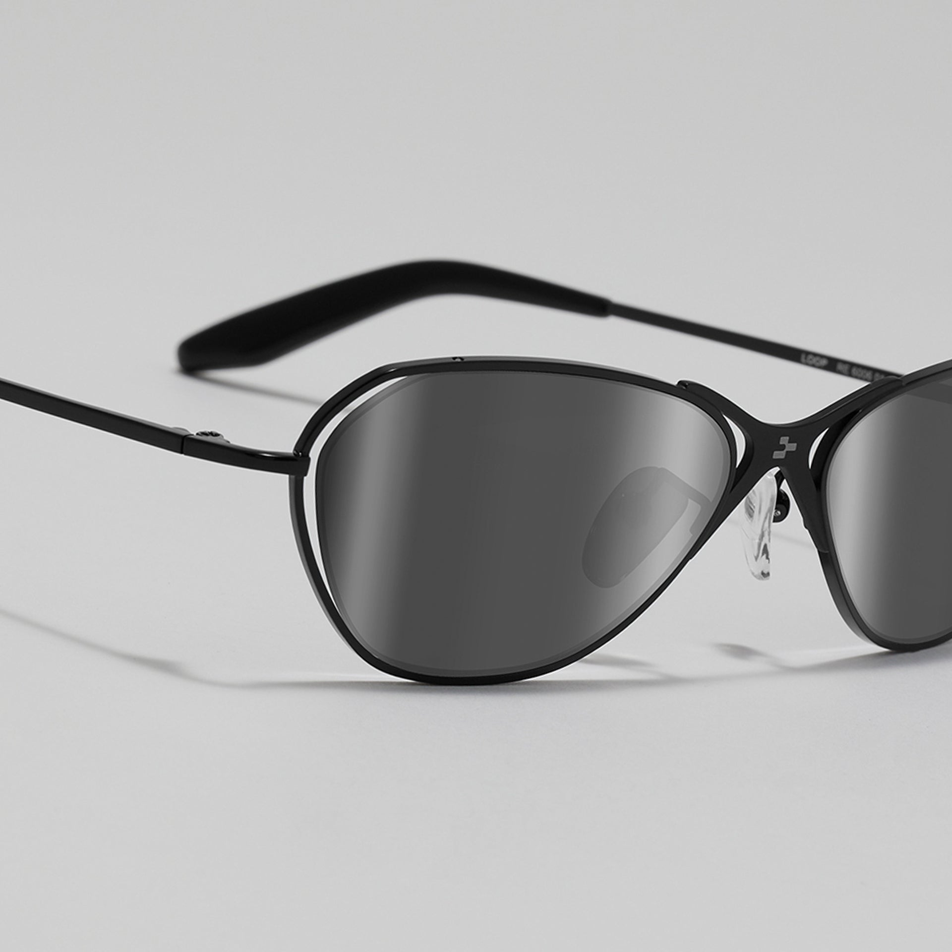 Sunglasses with black frame and dark lenses on a light gray background
