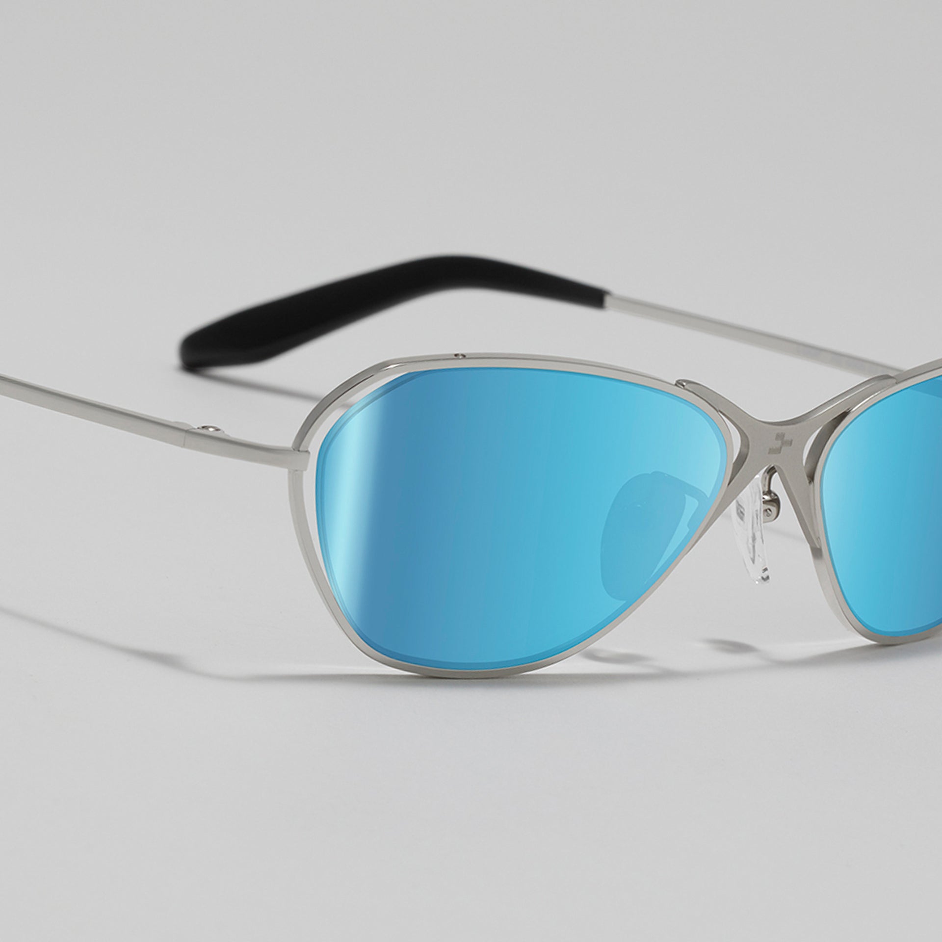 Sunglasses with blue lenses and silver frames on a light gray background