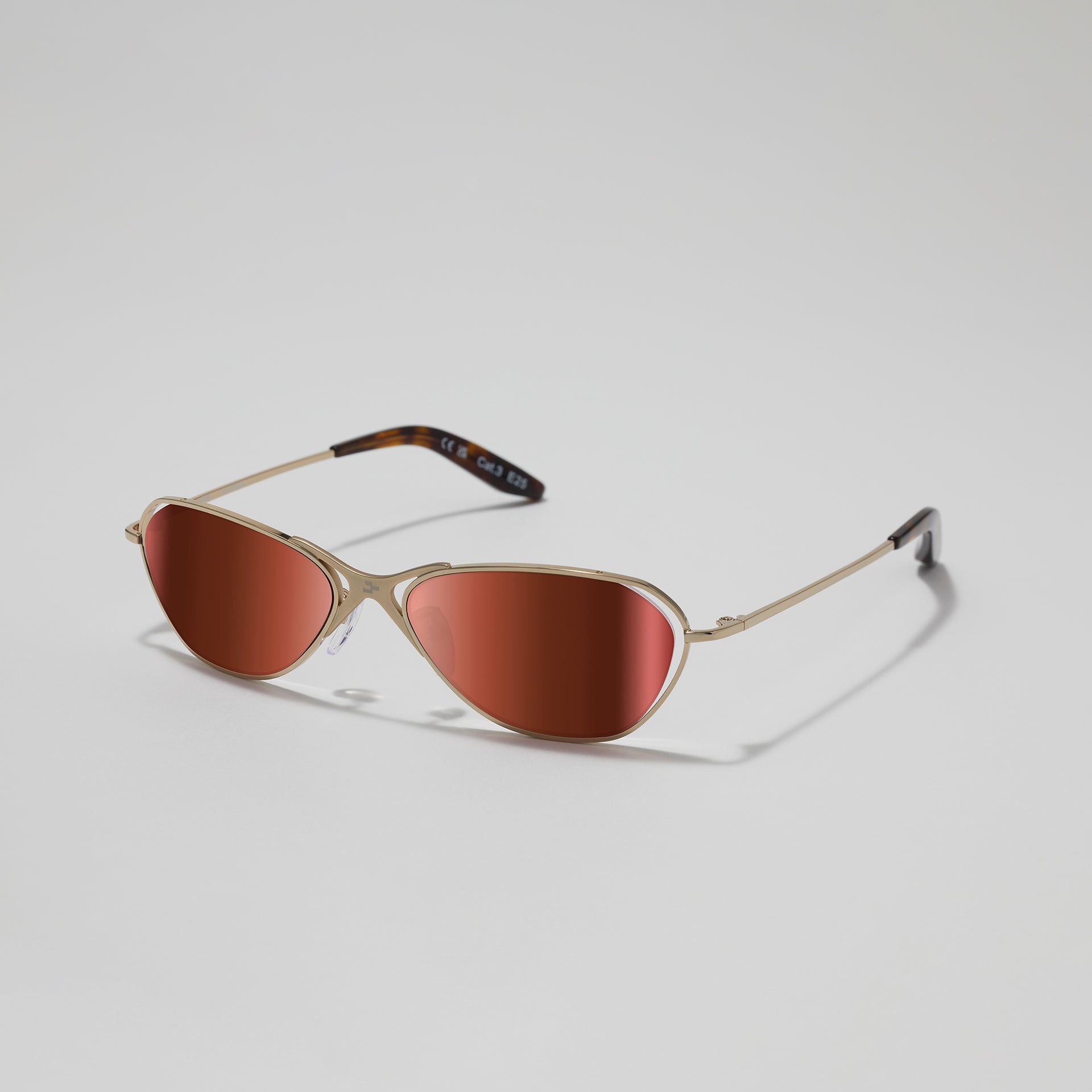 Sunglasses with gold frame and brown lenses on a light gray background