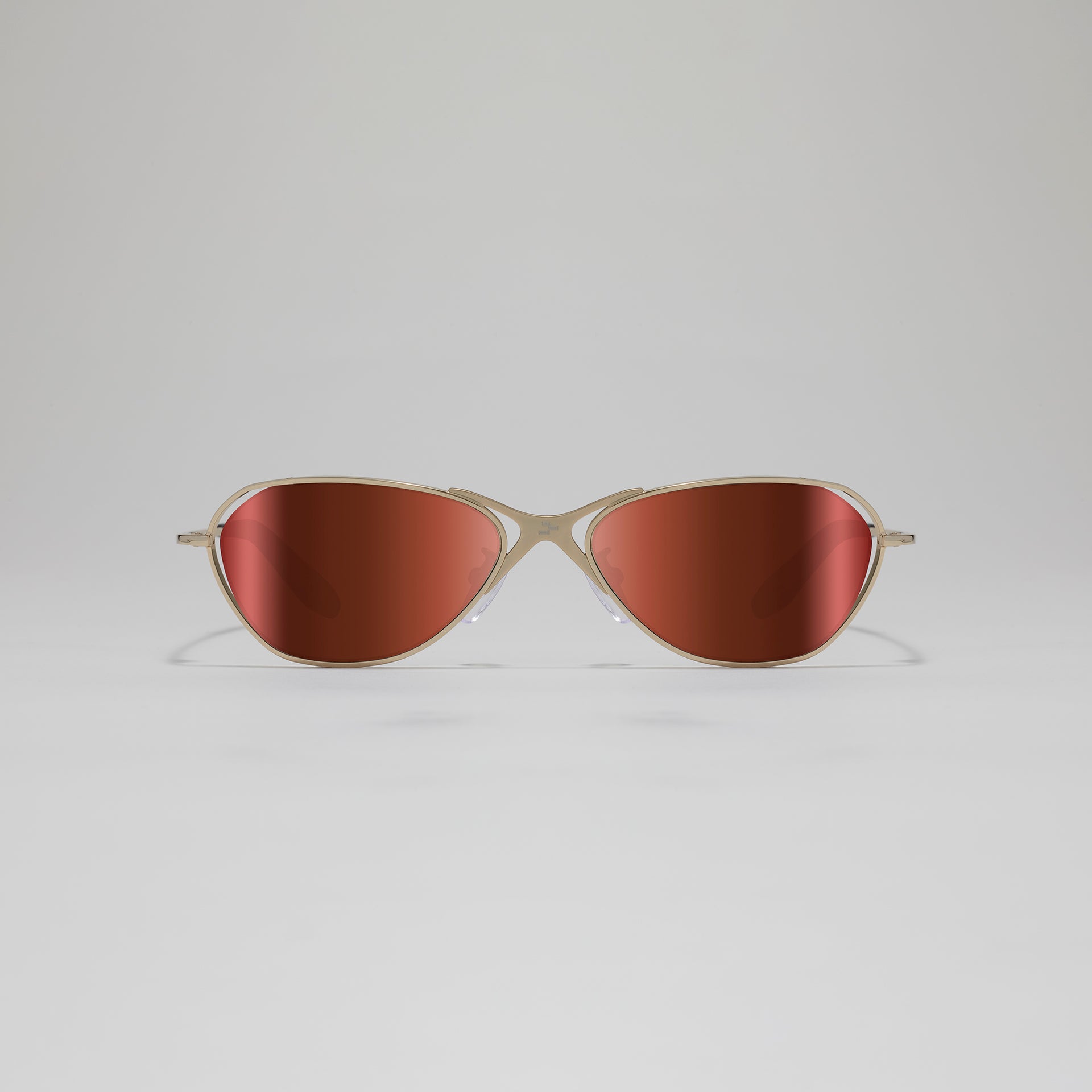 Sunglasses with gold frame and red-tinted lenses on a light gray background