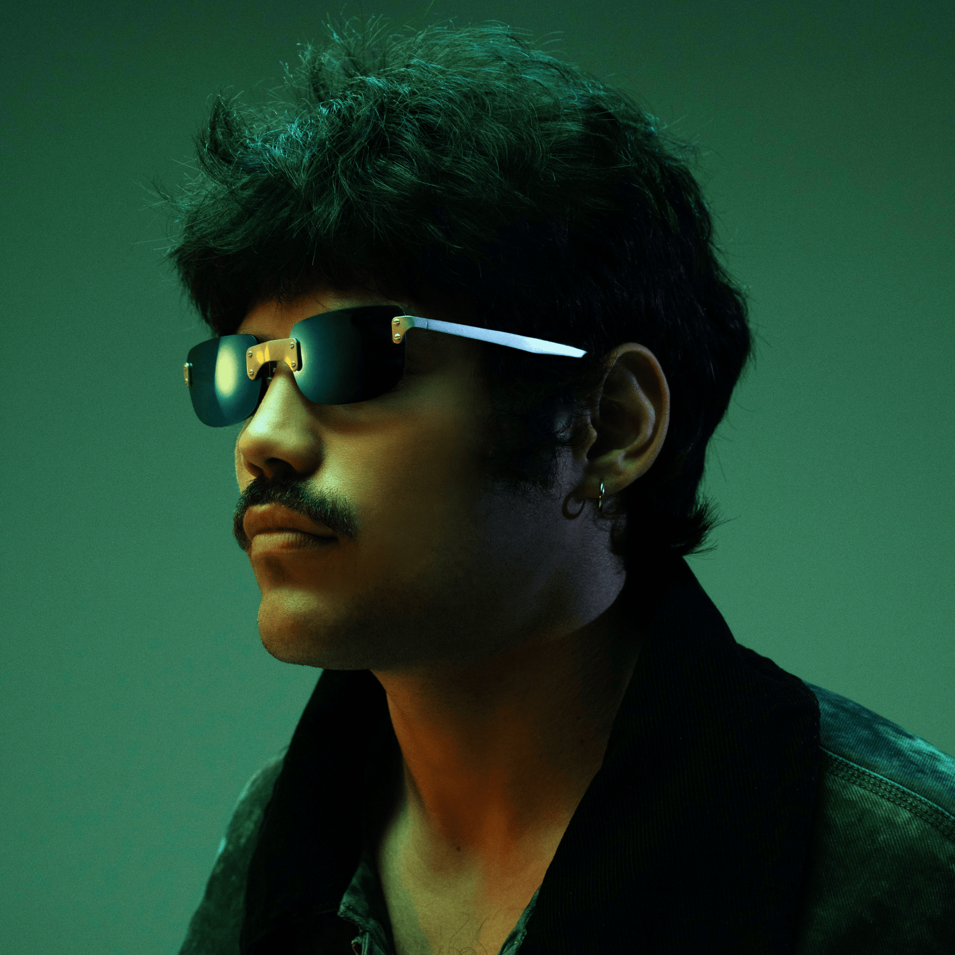 Person wearing sunglasses with a greenish tint against a dark background