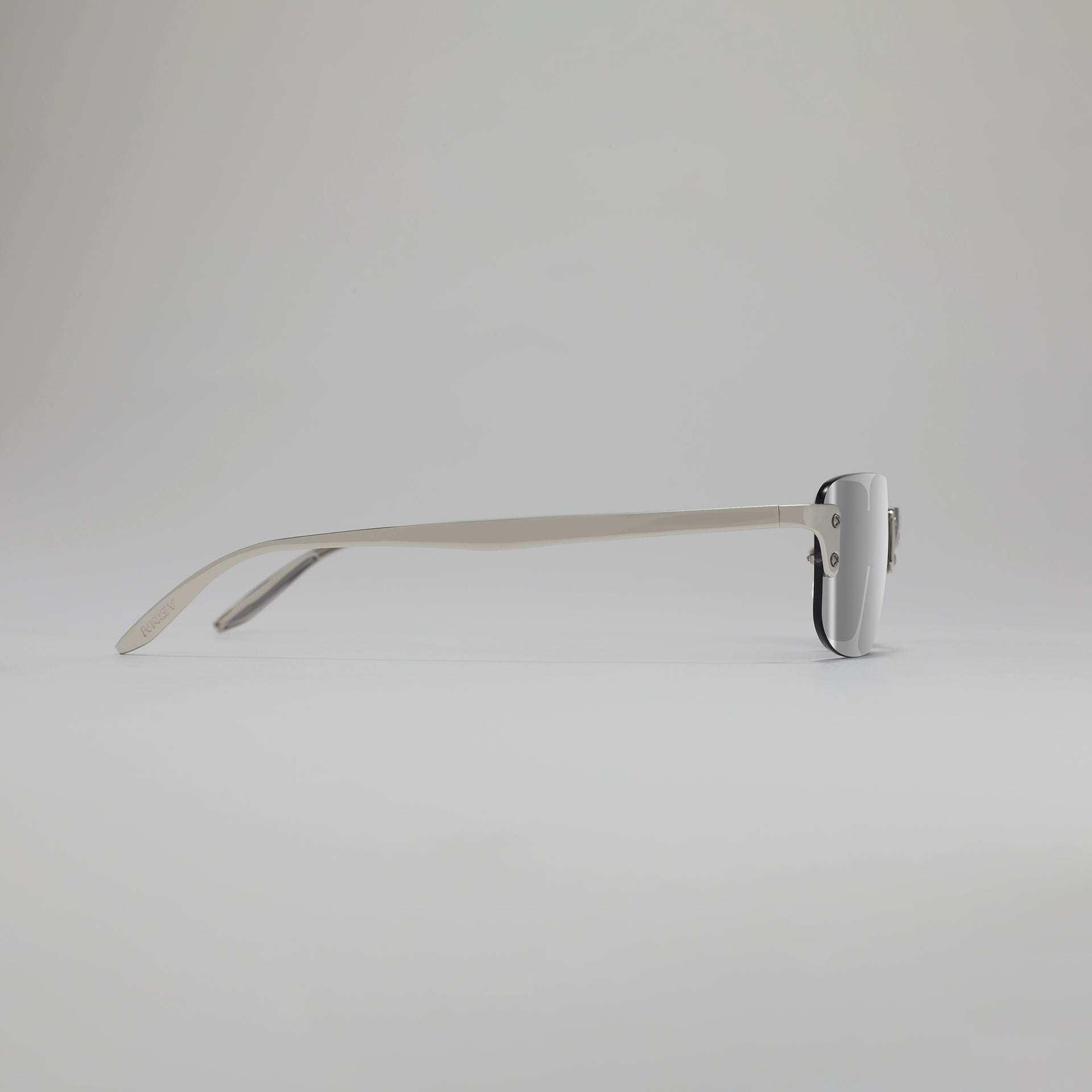 Silver sunglasses with a thin frame on a light gray background
