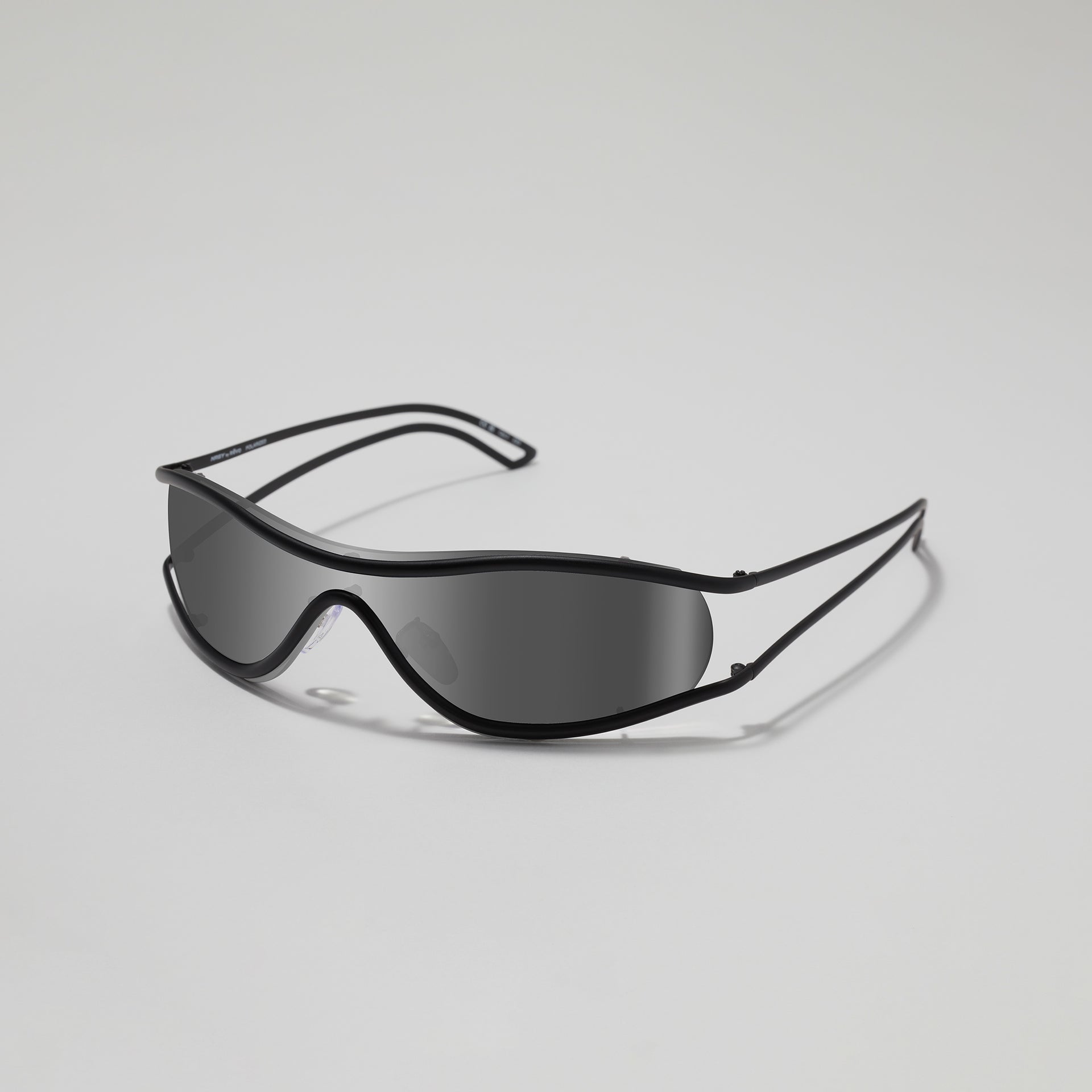 Black shield-style sunglasses on a light gray background