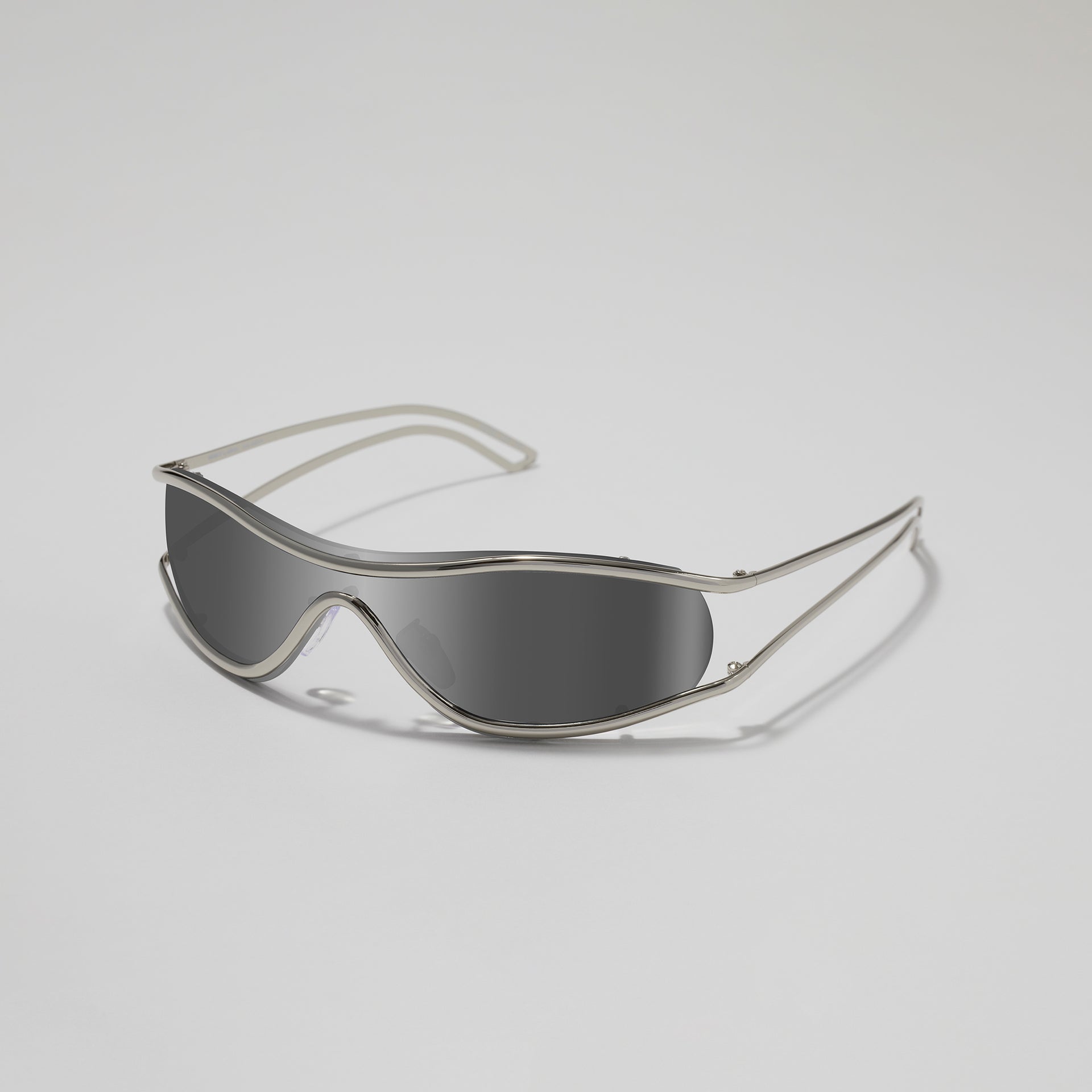 Silver sunglasses with dark lenses on a light gray background