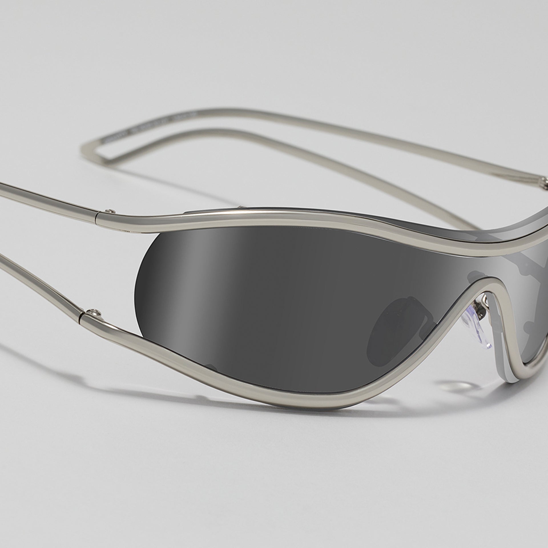 Silver sunglasses with dark lenses on a light gray background