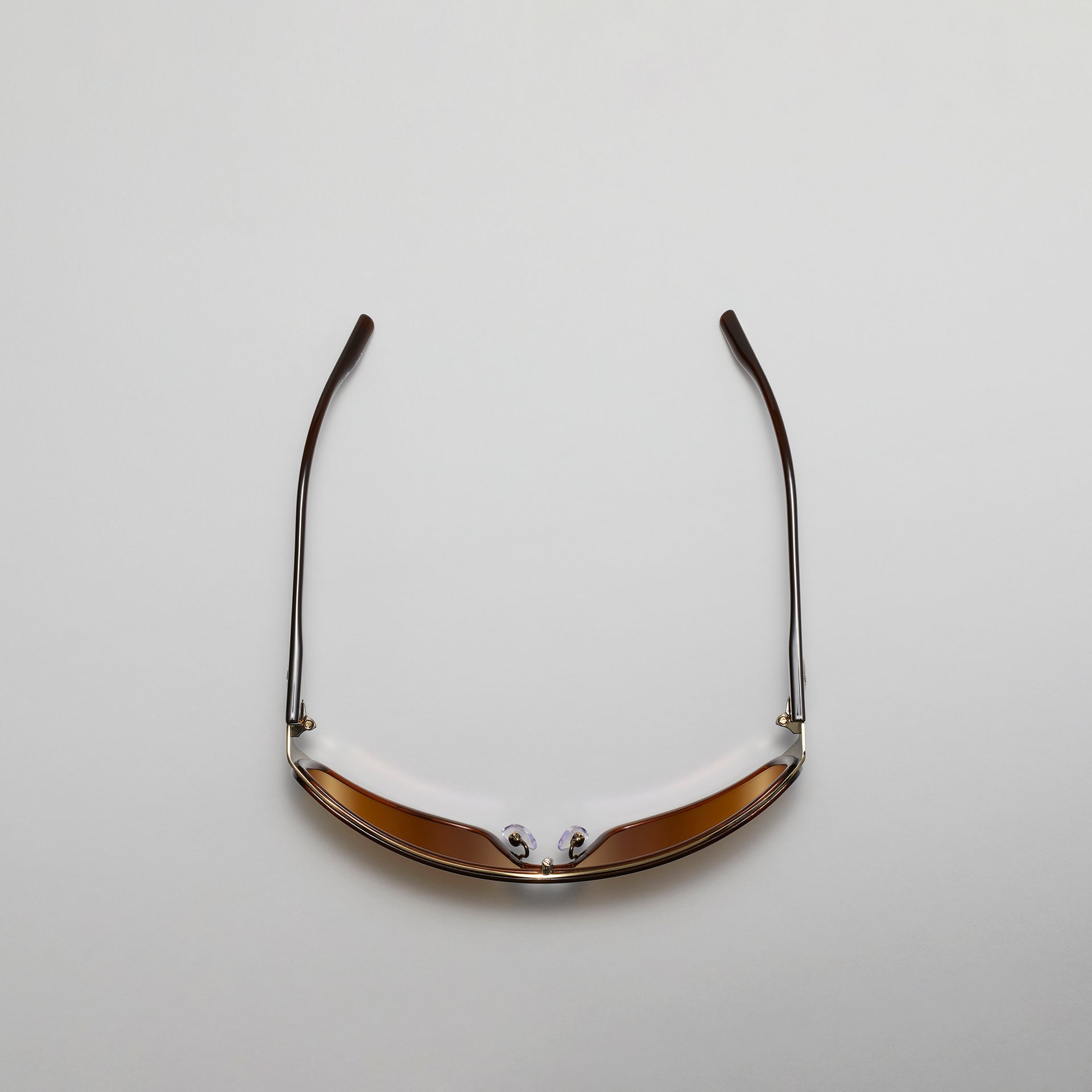 Sunglasses with gold frame and reflective lenses on a light gray background