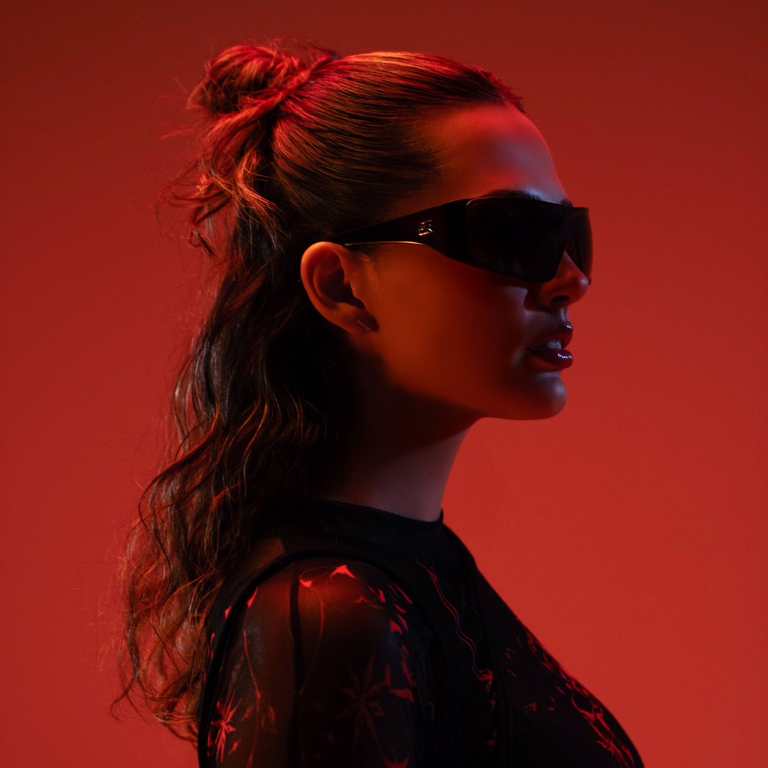 Woman wearing sunglasses against a red background