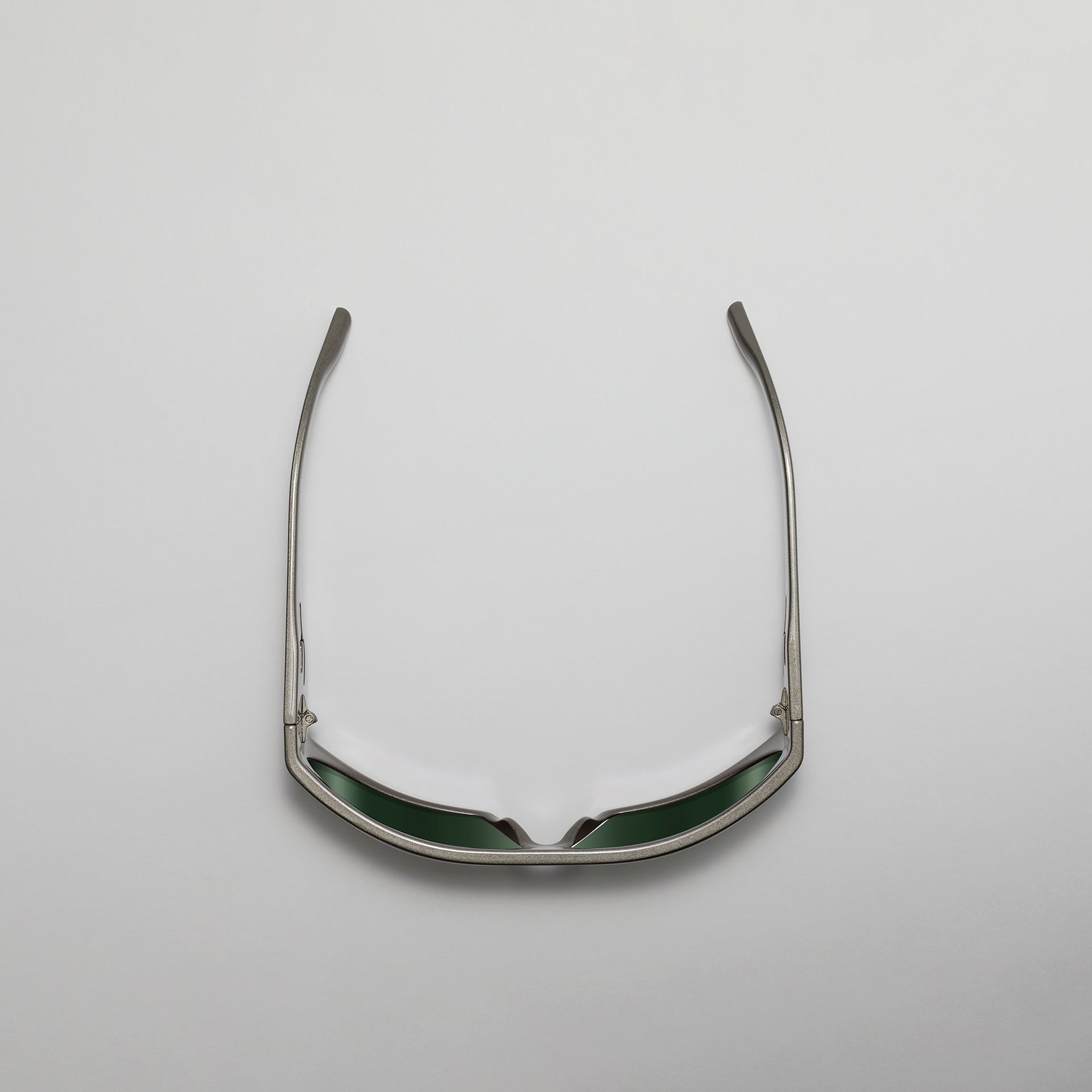 Sunglasses with green lenses and silver frame on a light gray background
