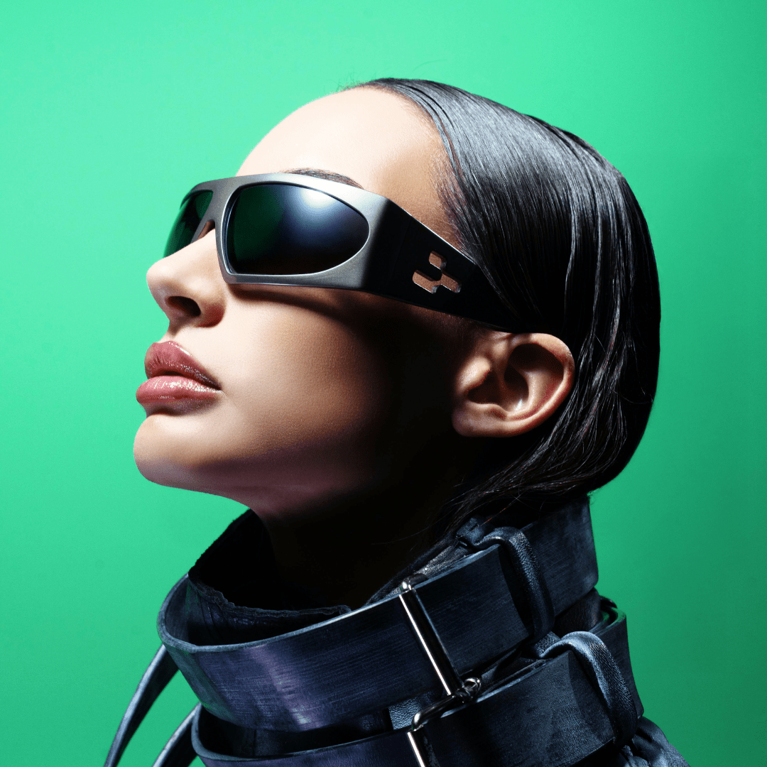 Person wearing futuristic sunglasses and black outfit against a green background
