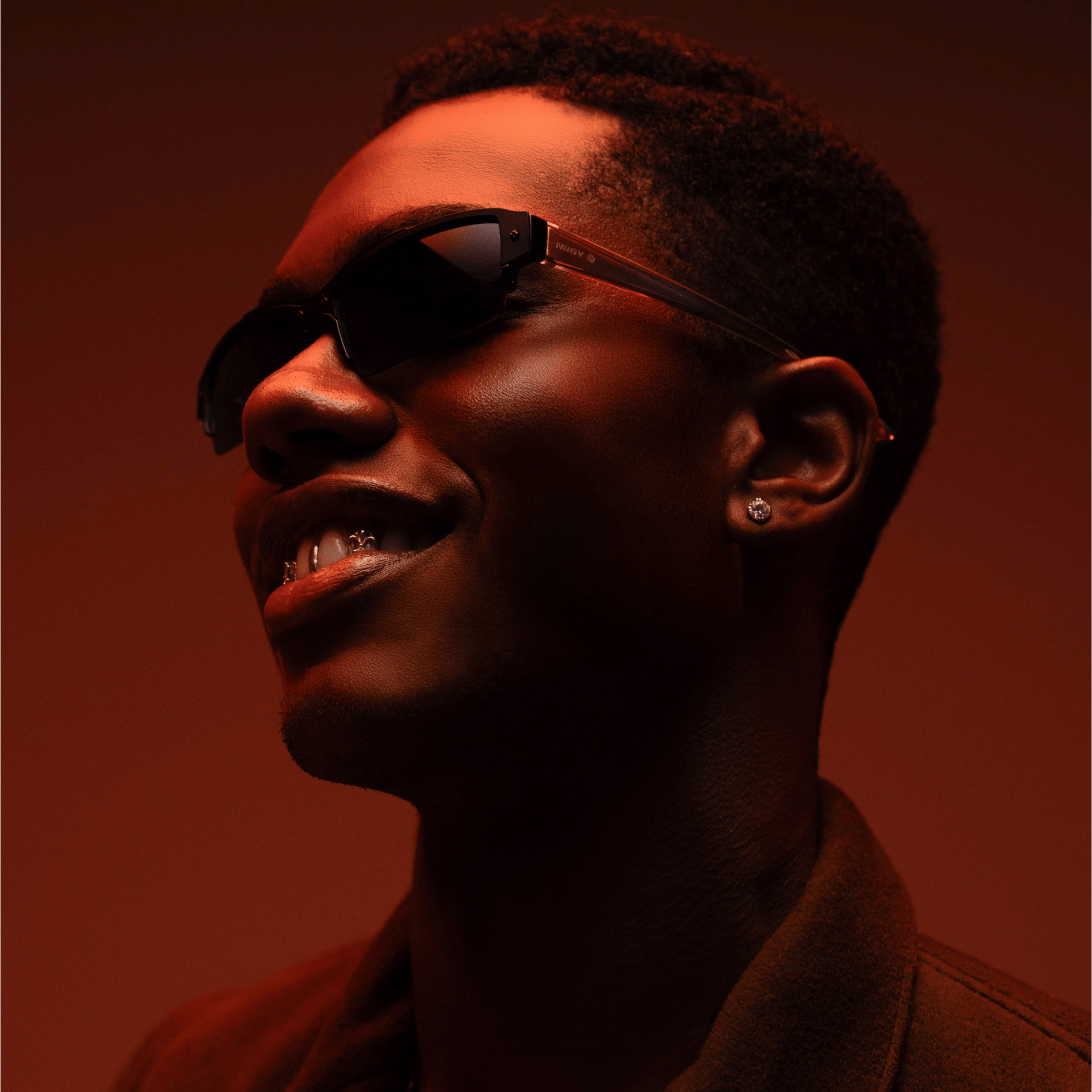 Person wearing sunglasses with a warm, reddish-brown background