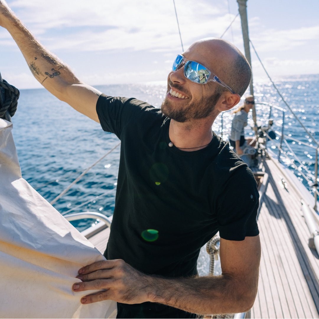 Man on a sailboat with ocean and sky in the background