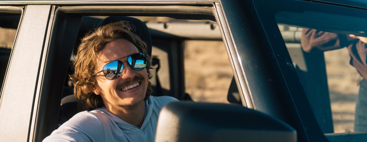 Man wearing sunglasses sitting in a car with a blurred background