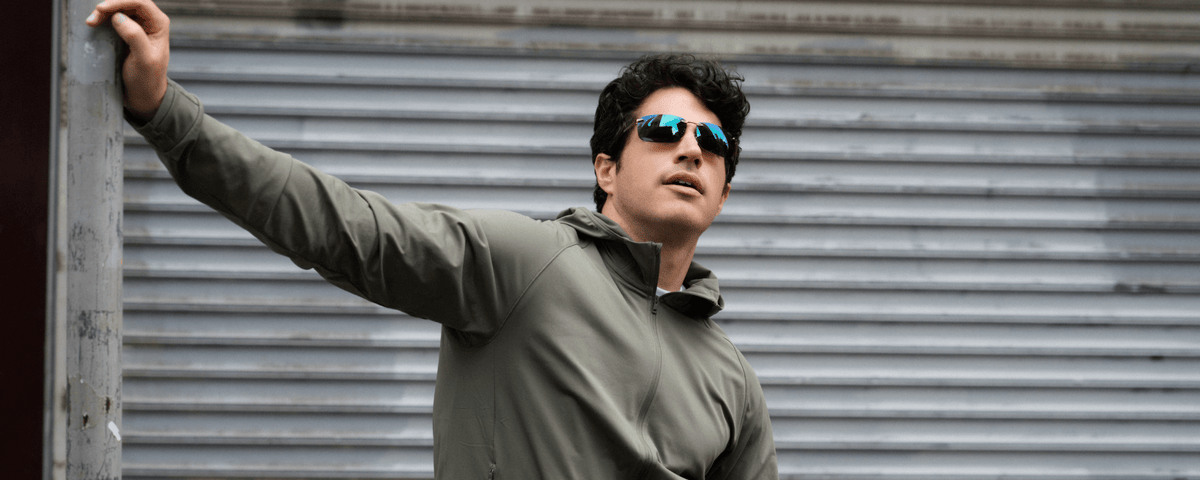 Man wearing metal frame sunglasses from the NEW collection leaning against a weathered post