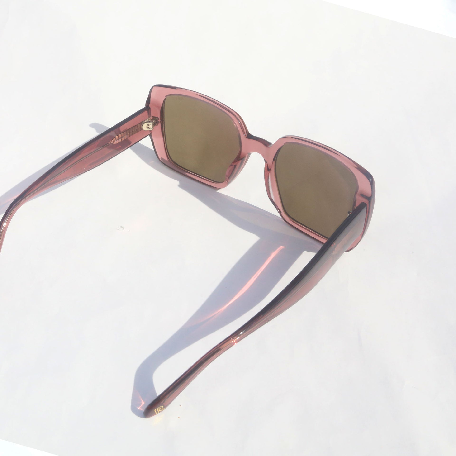 Sunglasses with pink frame and brown lenses on a white background