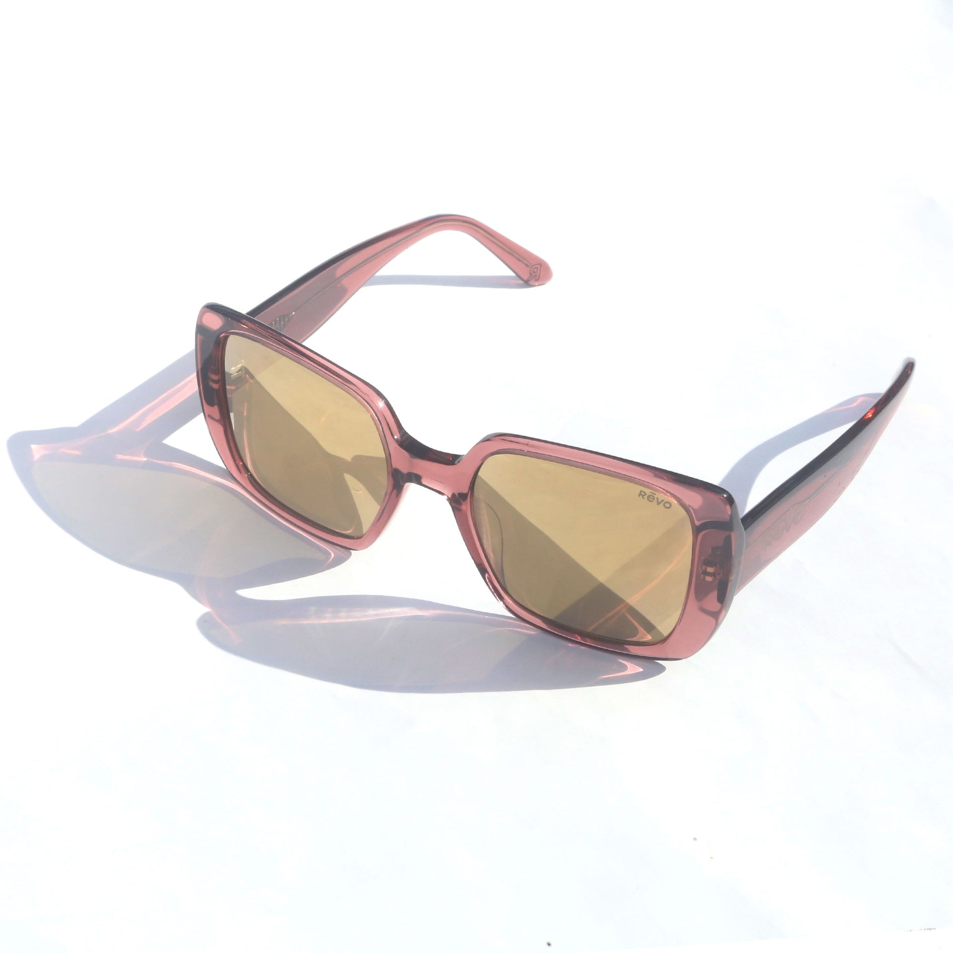 Sunglasses with pink frame and gold lenses on a white background
