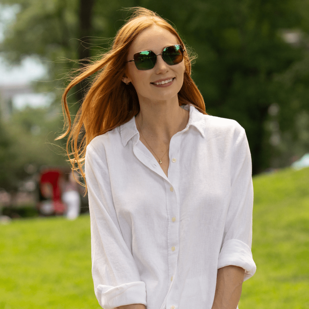 Bella oversized metal sunglasses with dark lenses on a smiling woman in a white shirt.