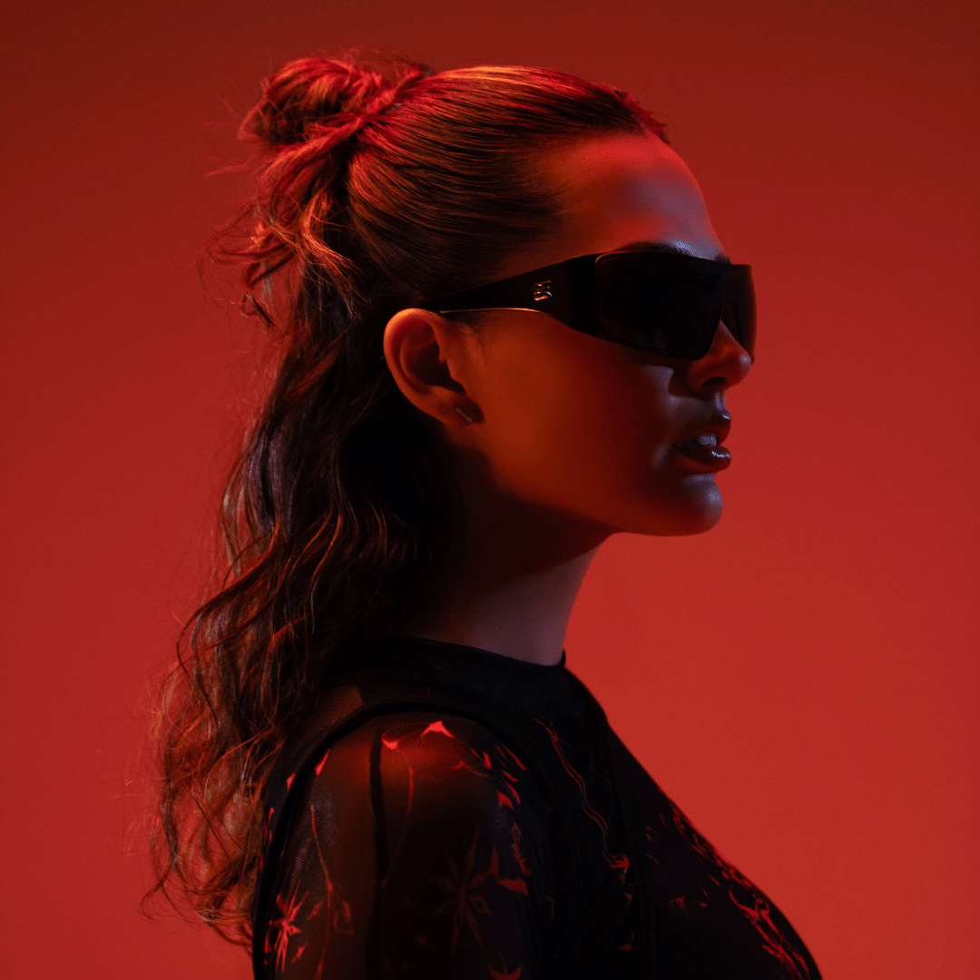Woman wearing sunglasses against a red background
