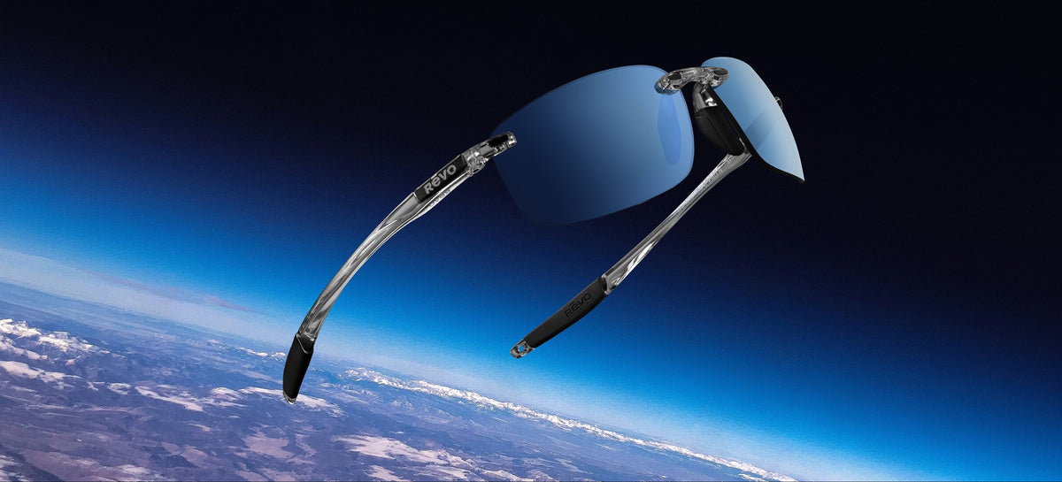 A pair of sport sunglasses with silver metal frames and blue mirrored lenses, floating against a background of Earth from space.