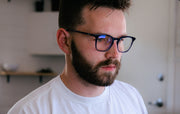Man working on computer and wearing vintage keyhole square blue light blocking glasses with clear blue frame